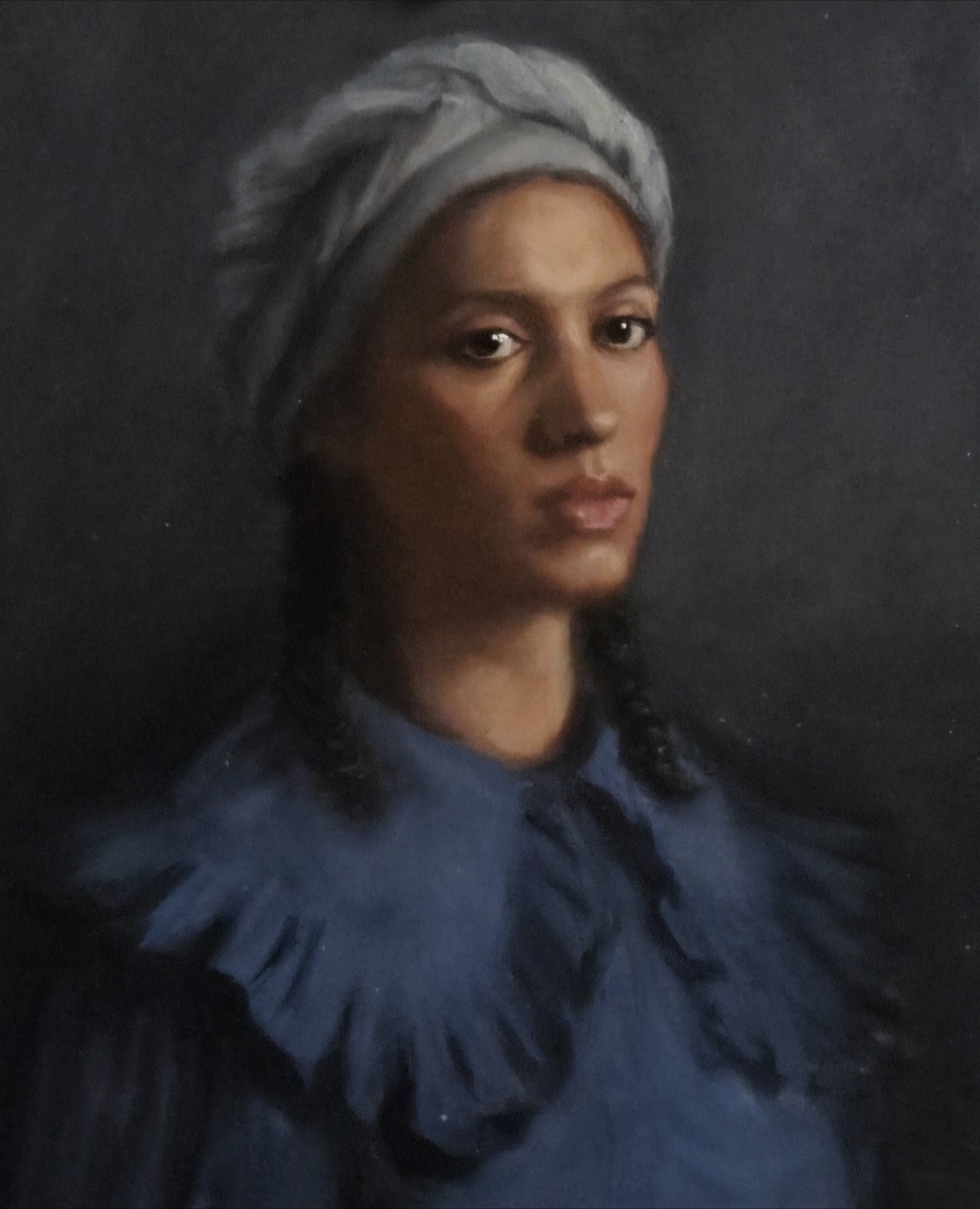 Portrait of a woman wearing a grey headwrap and blue blouse